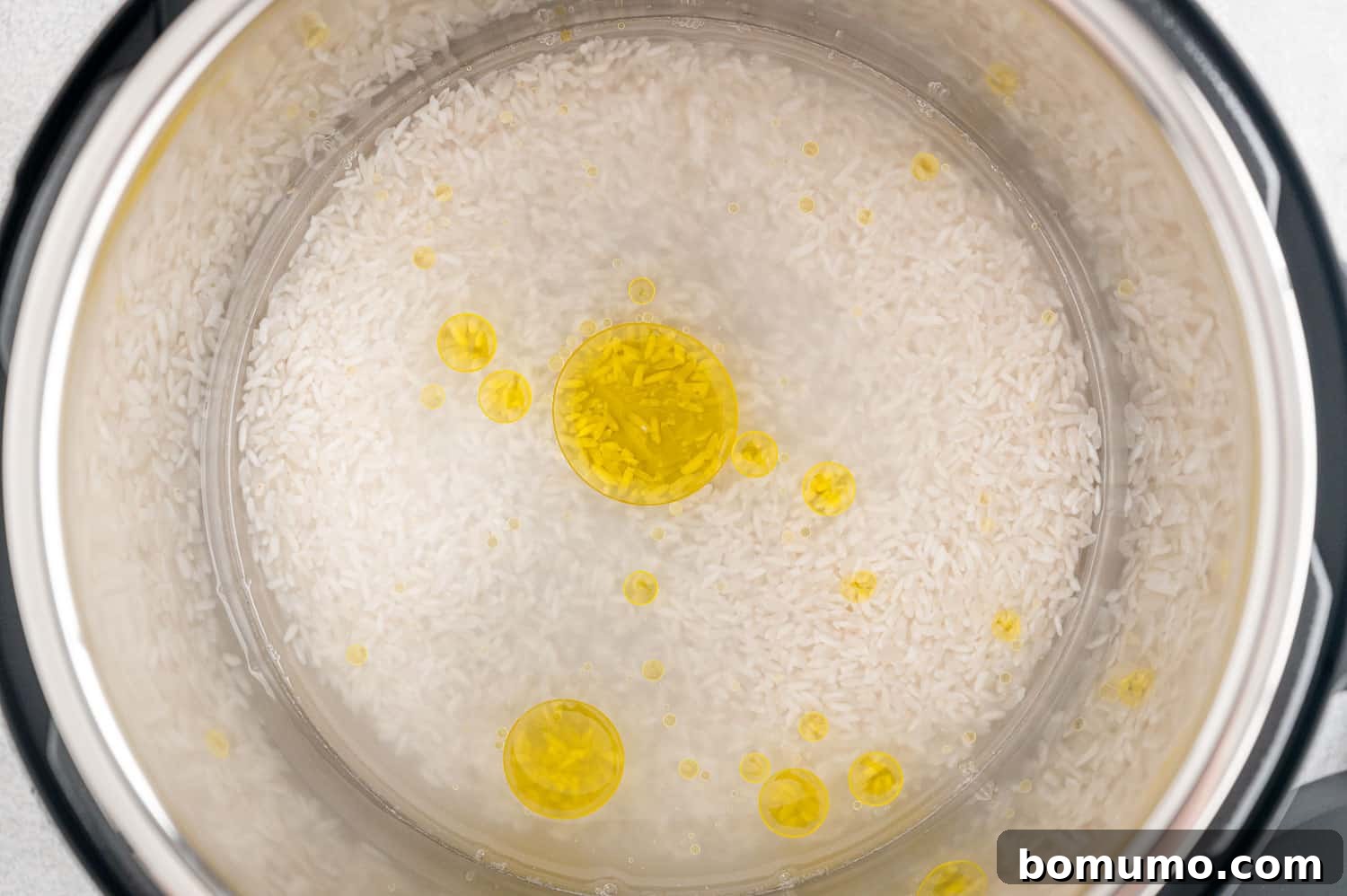 Uncooked rice, olive oil, and water added to the Instant Pot insert.