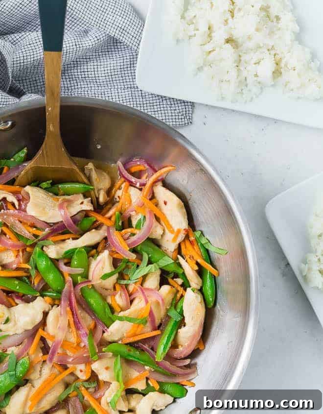 Zesty Ginger Basil Chicken 3 A vibrant Ginger Chicken Stir-Fry sizzling in a large wok, featuring golden chicken pieces, crisp sugar snap peas, bright carrots, and red onions, ready to be tossed with its aromatic sauce.