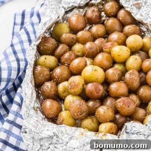 A pound and a half of baby potatoes, partially wrapped in foil. Specks of rosemary are pictured, as well as a blue and white linen.