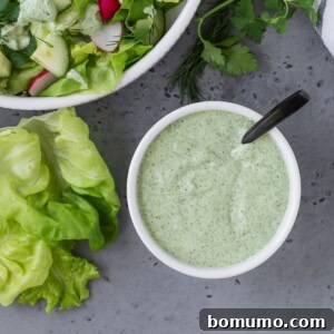 Overhead view of green goddess dressing in a small white bowl.