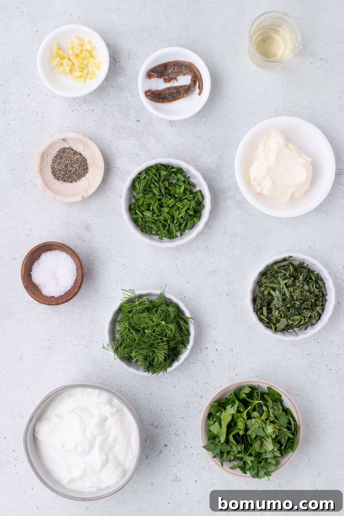 An organized overhead shot displaying all the fresh, vibrant ingredients required to prepare the healthy green goddess dressing.