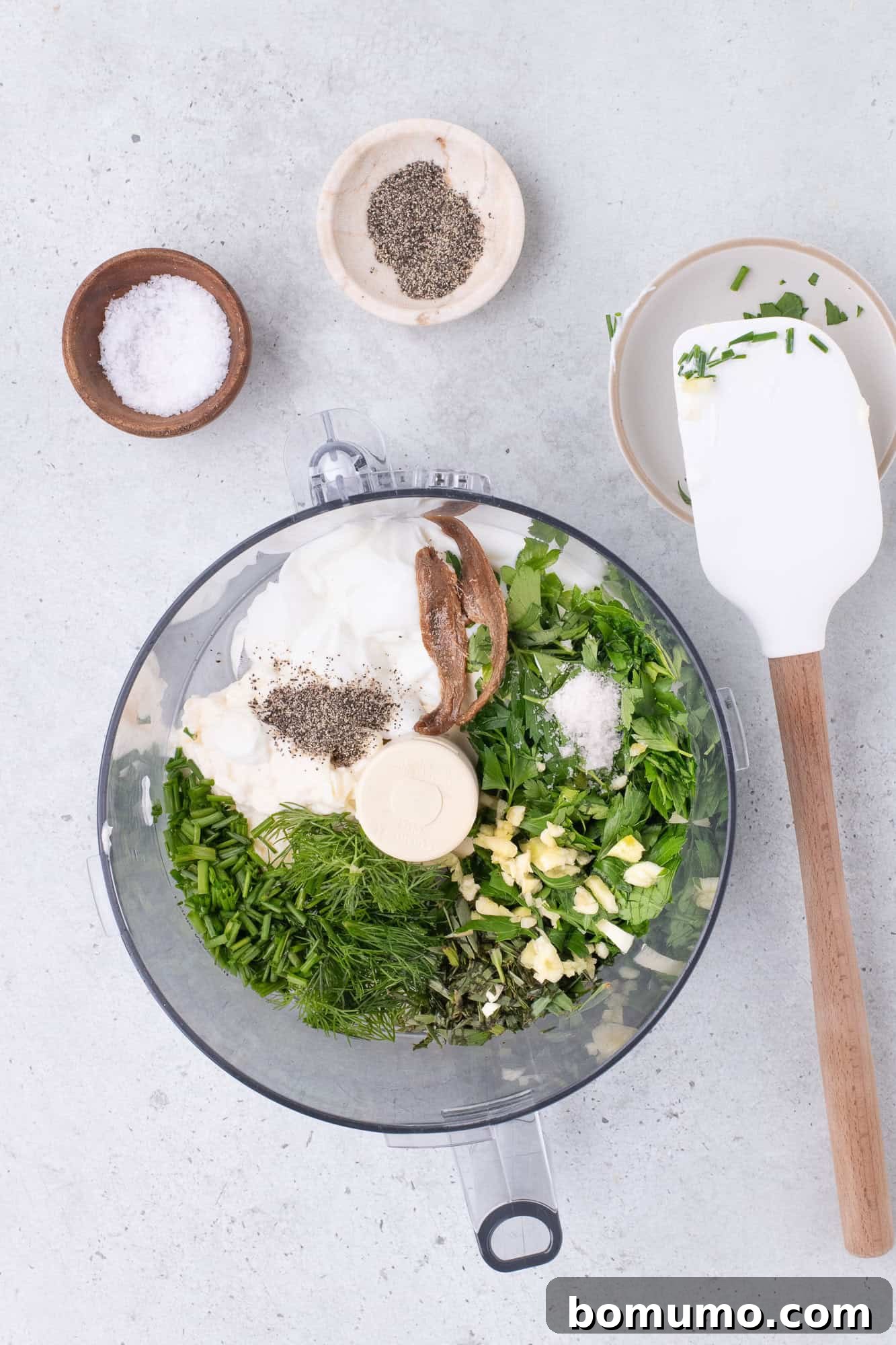 All the fresh ingredients for green goddess dressing placed in a food processor, ready for blending.
