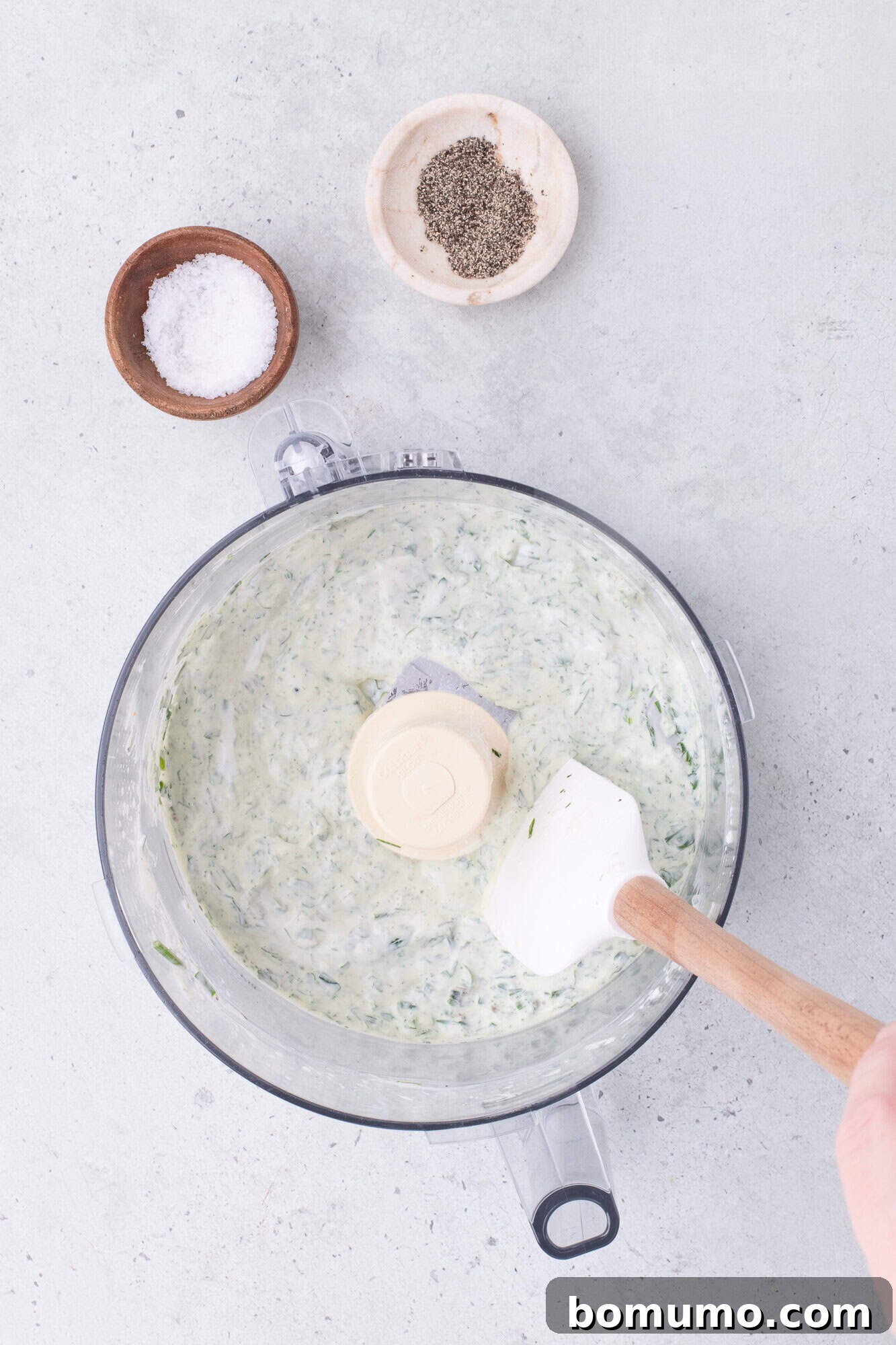 The ingredients for green goddess dressing in a food processor, showing the initial stages of blending into a creamy mixture.