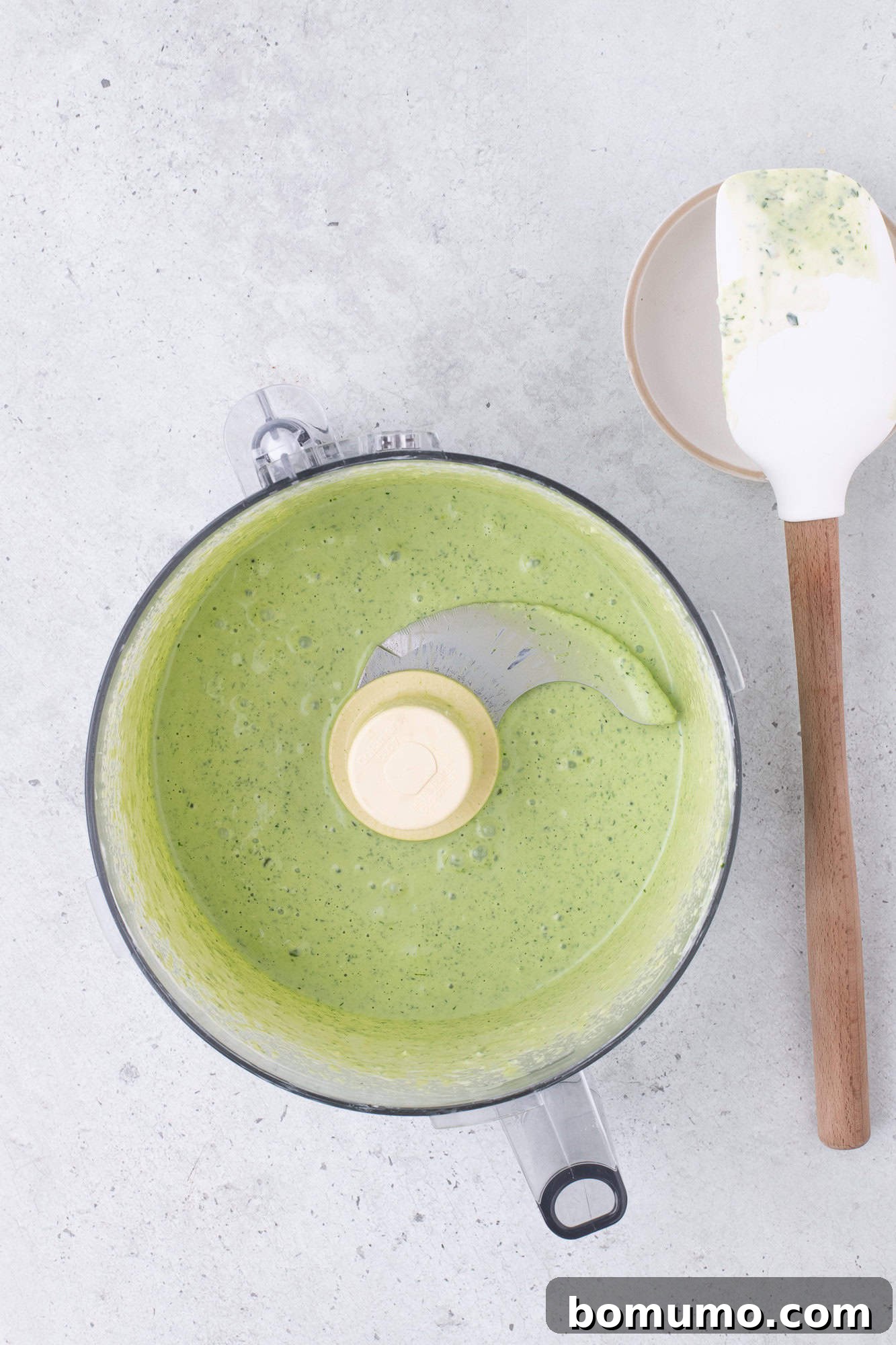Finished green goddess dressing, smooth and vibrant, resting in the food processor bowl after blending.