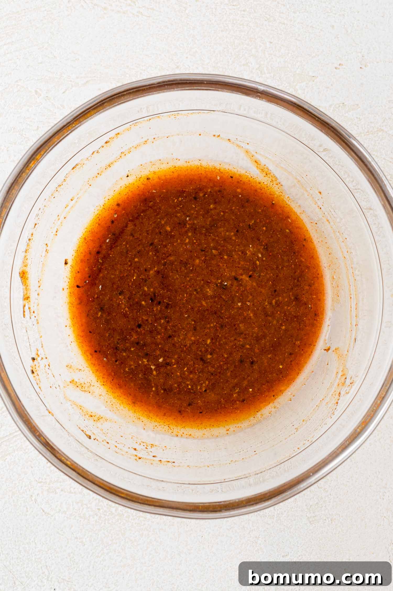 A glass bowl contains a reddish-brown liquid mixture with visible specks.