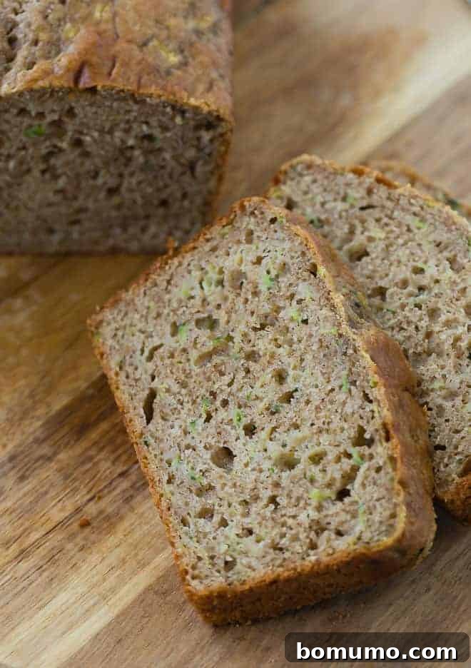 A close-up view of a perfectly sliced loaf of whole wheat zucchini bread, revealing its moist, tender interior.