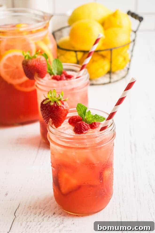 Light red drink in glasses with red and white striped paper straws.