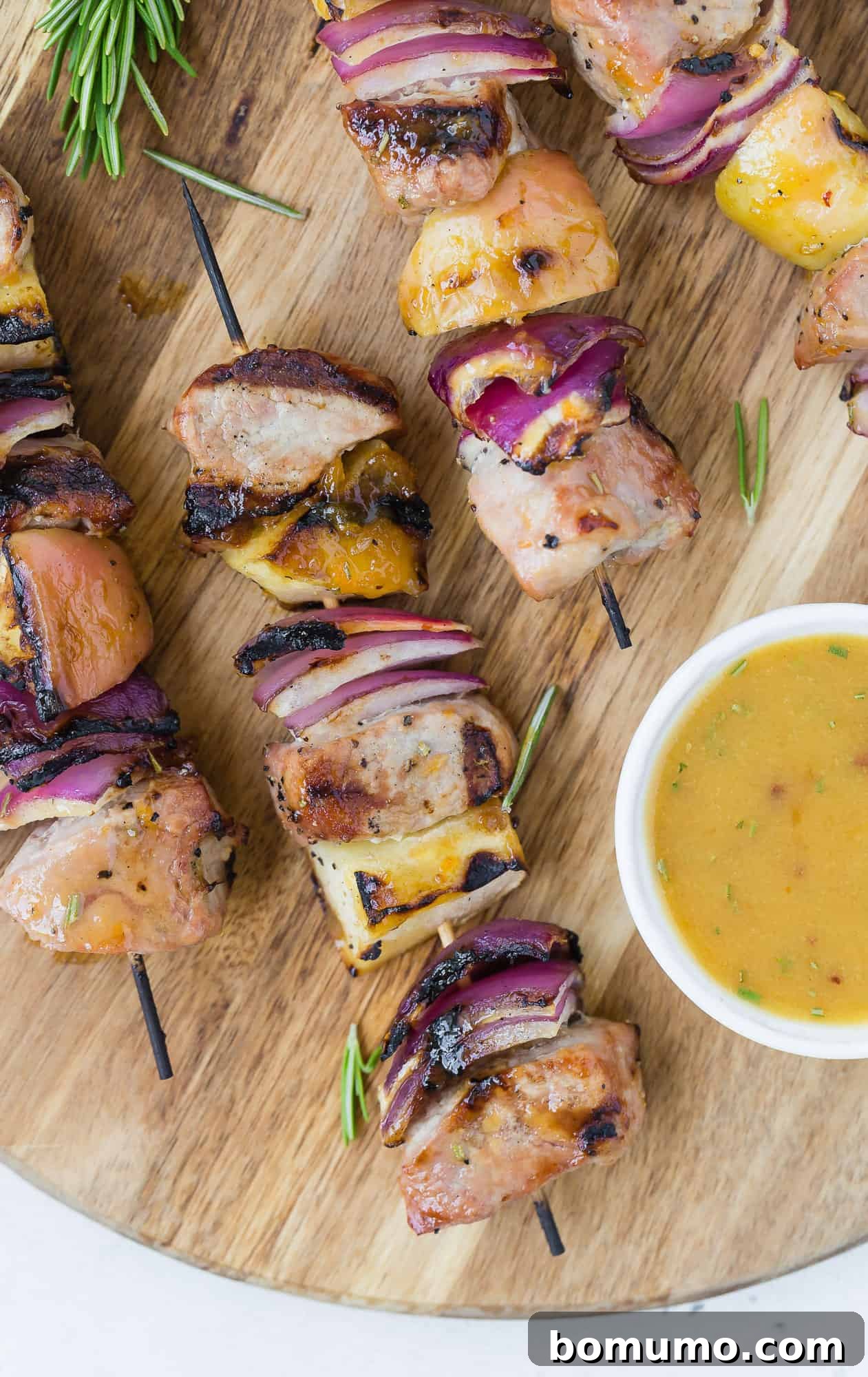 Grilled Pork Kabobs with Apples and Red Onions on a rustic wooden cutting board, ready to be served.