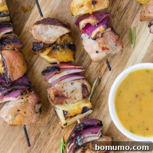 Pork kebobs with apples and onions, served with sauce.