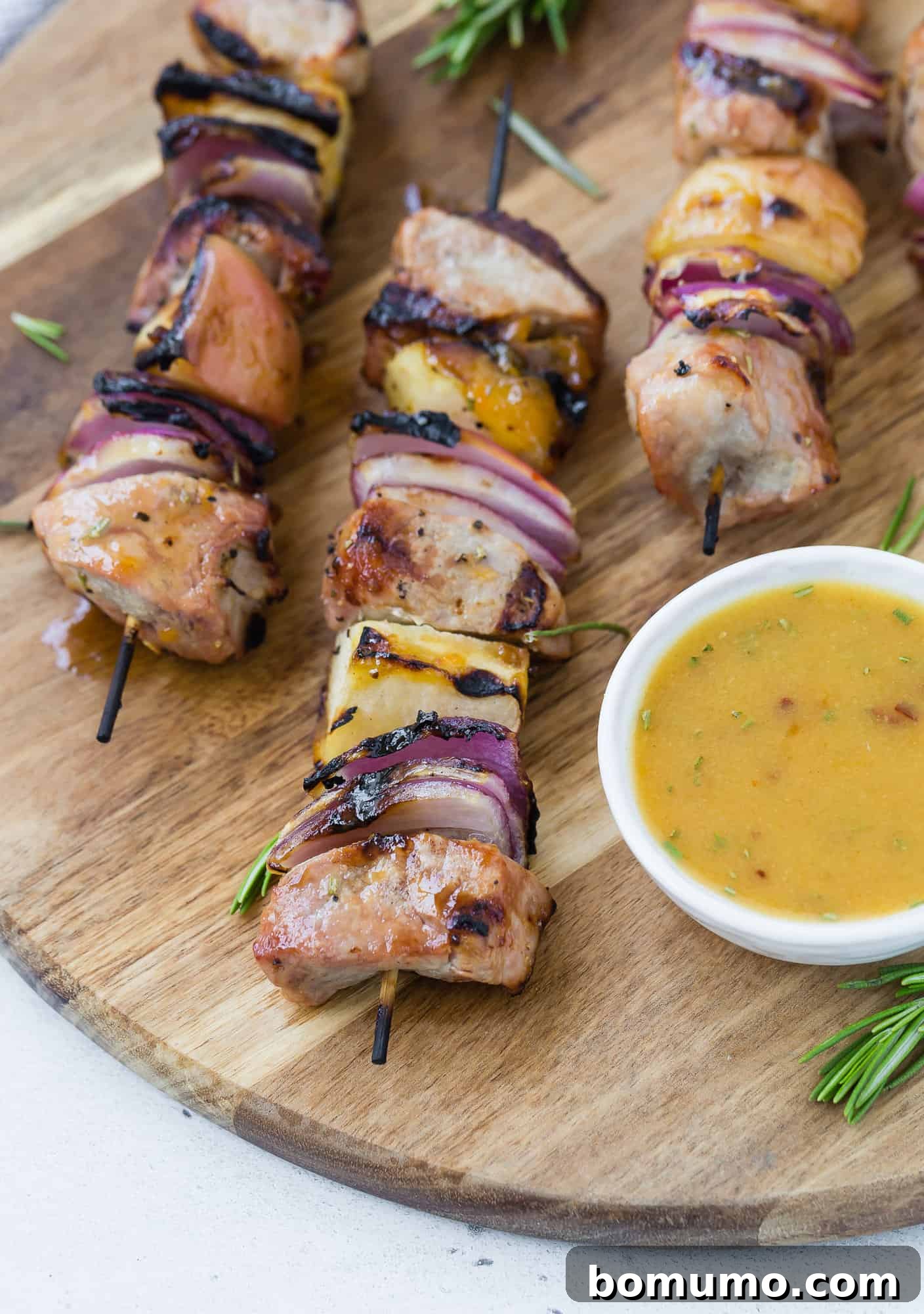 Assortment of pork cubes, apple pieces, and red onion chunks threaded onto skewers, showcasing the vibrant ingredients of the dish.