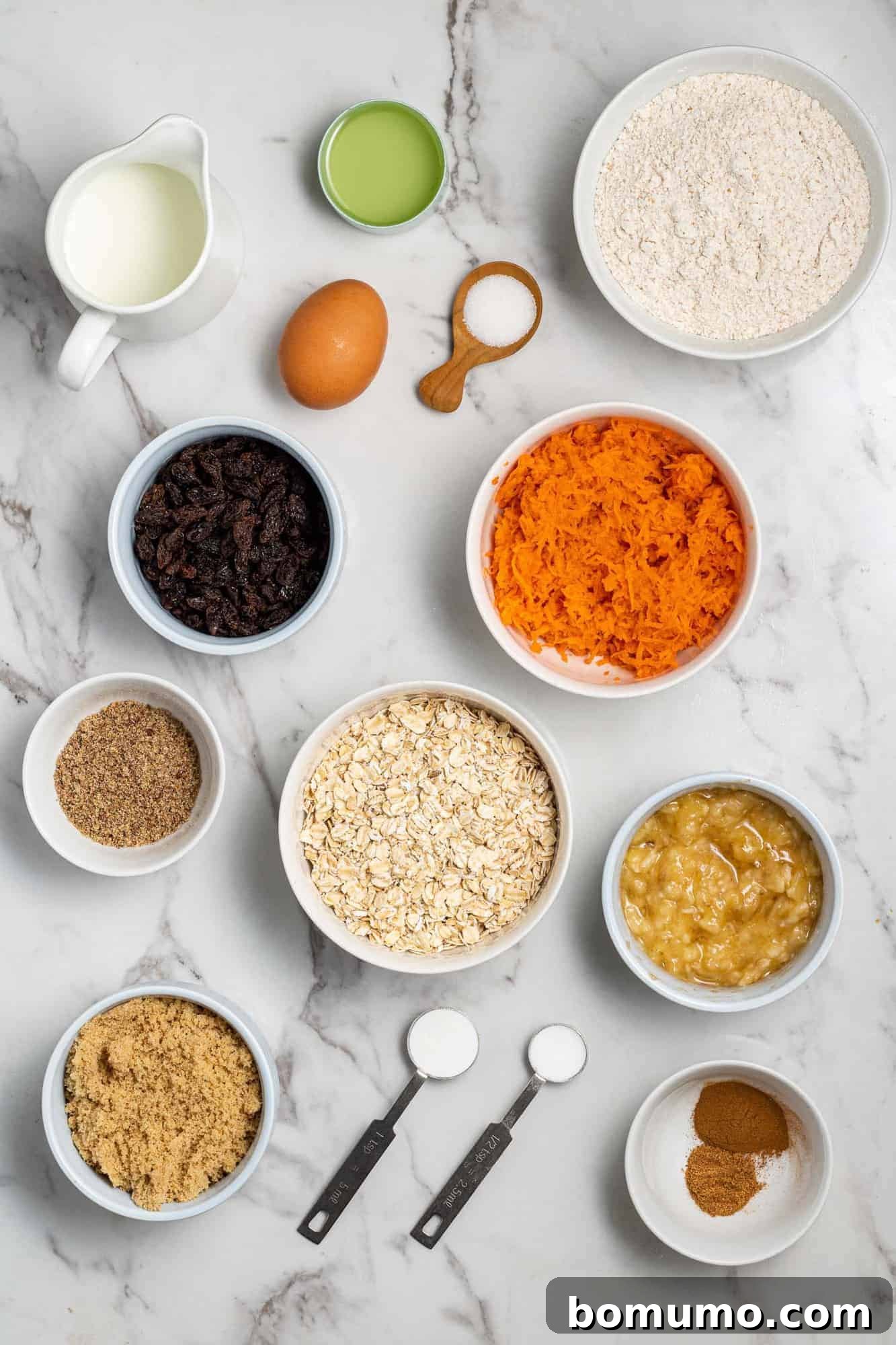 An overhead view showcasing all the fresh and dry ingredients neatly laid out for the carrot raisin muffin recipe.