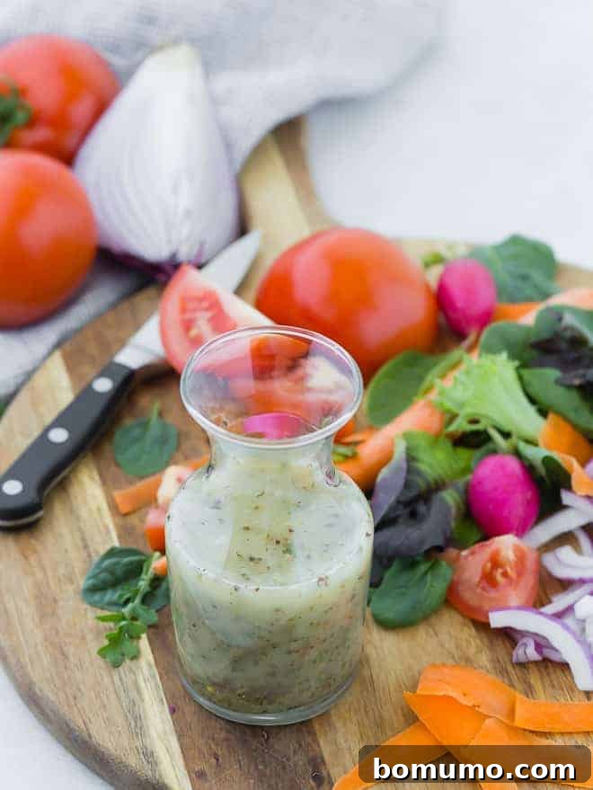 Authentic Italian Dressing from Scratch 4 Small glass bottle of homemade italian dressing on wooden cutting board surrounded by colorful vegetables.