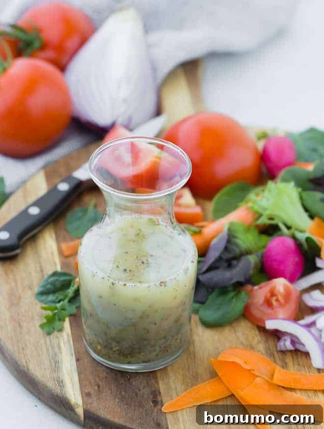 Authentic Italian Dressing from Scratch 5 Small glass bottle of homemade italian dressing on wooden cutting board surrounded by colorful vegetables.