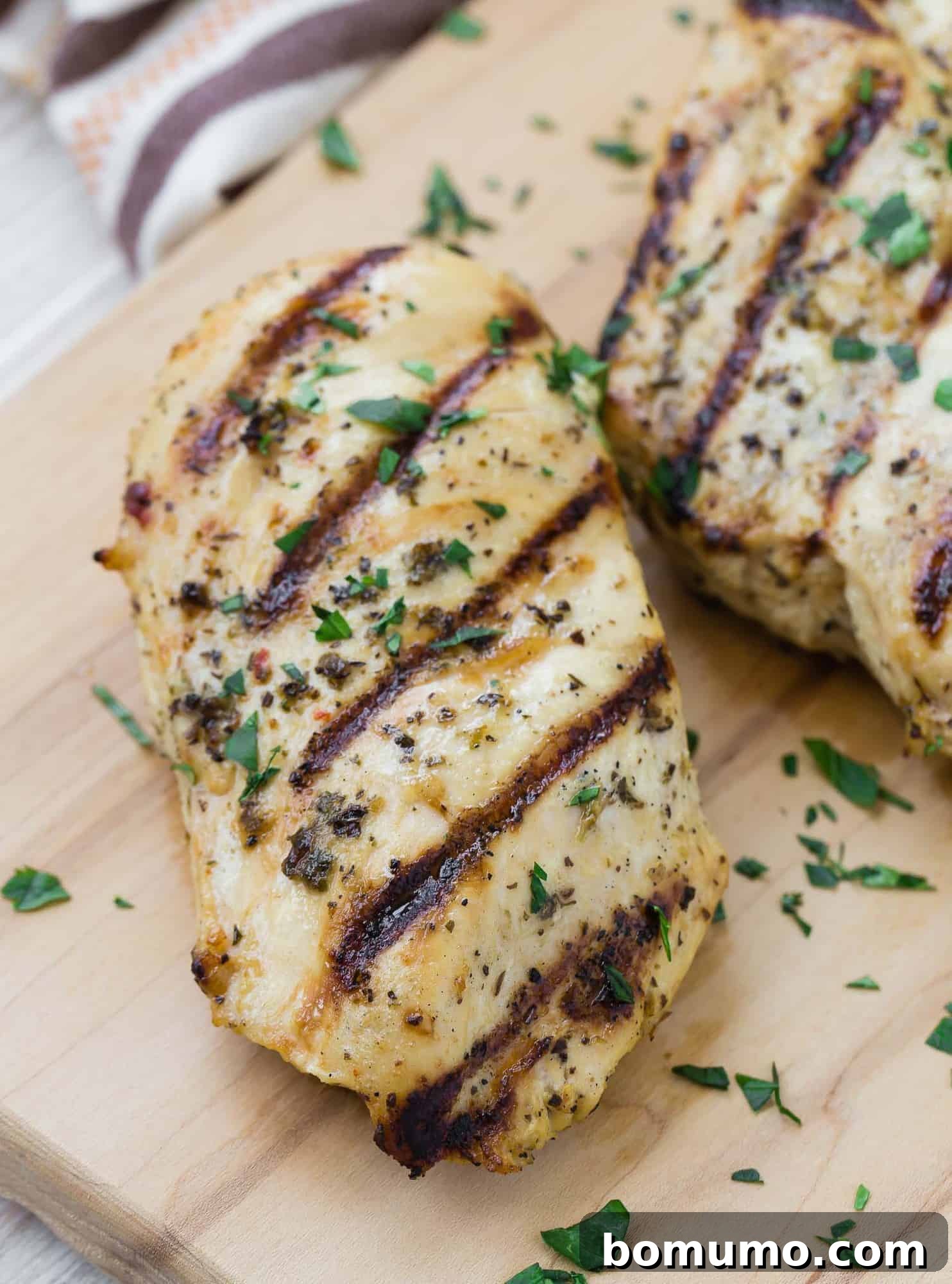 A marinated grilled chicken breast topped with chopped fresh parsley.