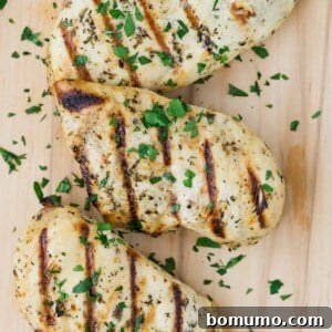 Close up view of a grilled chicken breast marinated in Italian chicken marinade. It is sprinkled with chopped fresh parsley.