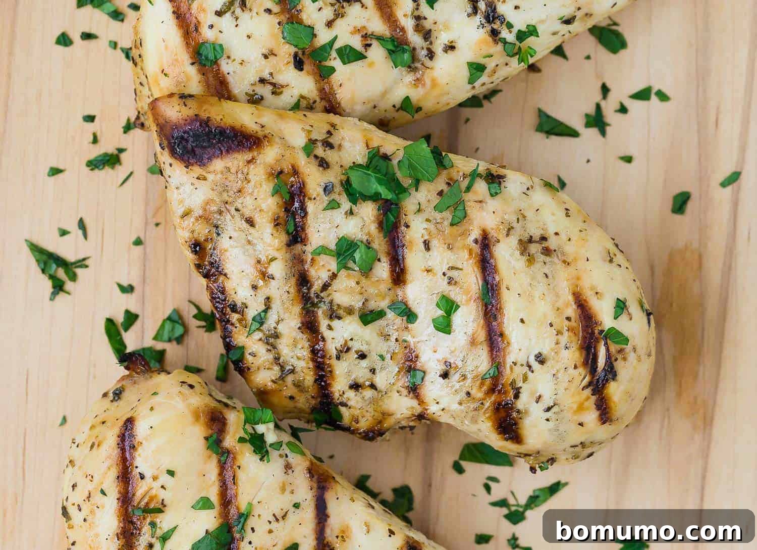 Close up view of a grilled chicken breast marinated in Italian chicken marinade. It is sprinkled with chopped fresh parsley.
