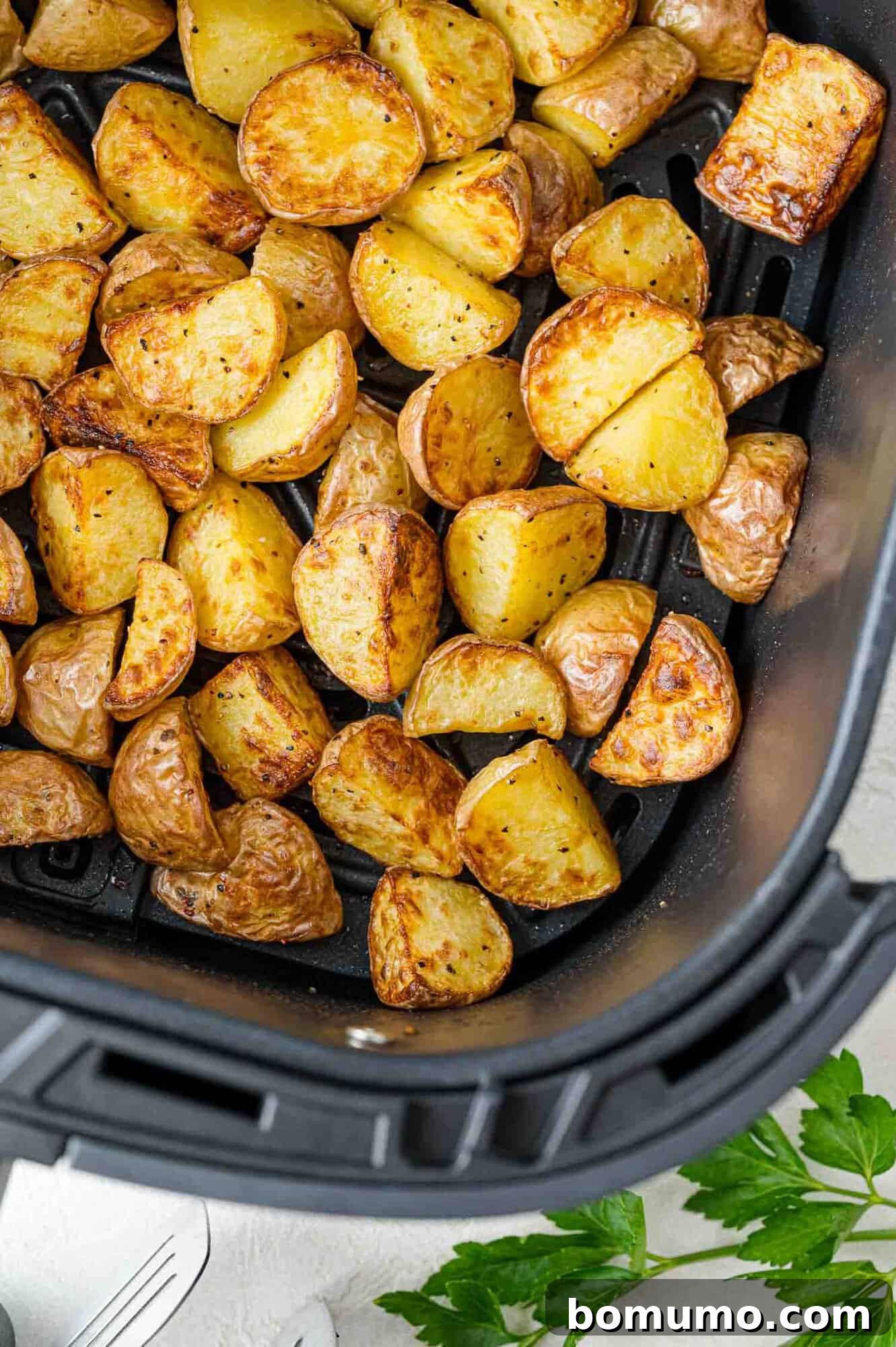 Golden brown, crispy halved baby potatoes cooked in an air fryer basket, ready to serve.