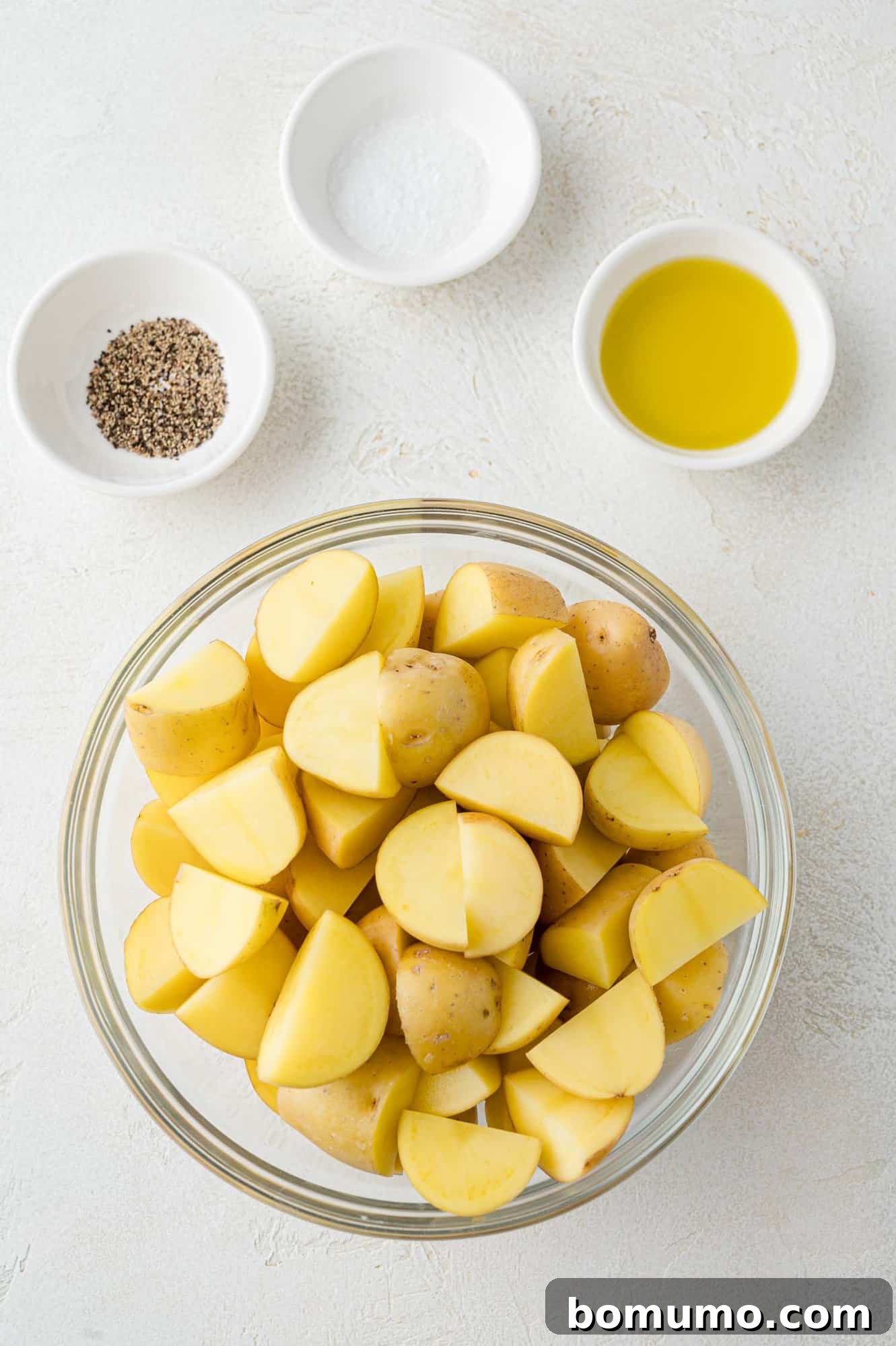 A selection of ingredients laid out on a counter, specifically potatoes, olive oil, and seasonings, ready for the recipe.