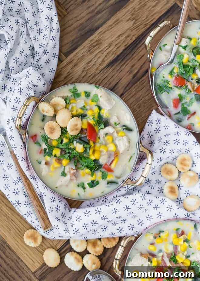 Wholesome Chicken Corn Chowder 2 Overhead view of three bowls of creamy chicken corn chowder, topped with crunchy oyster crackers and fresh cilantro, promising a delightful culinary experience.
