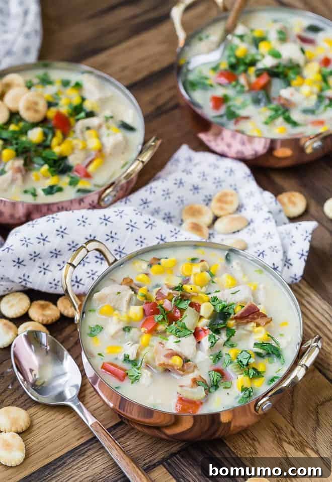 Wholesome Chicken Corn Chowder 5 Three bowls of vibrant chicken corn chowder, showcasing a rich blend of corn, red bell peppers, poblano peppers, chicken, and fresh cilantro, perfectly garnished with oyster crackers.