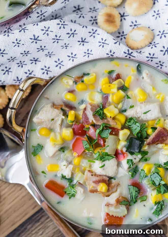 Wholesome Chicken Corn Chowder 6 Close-up view of a steaming bowl of chicken corn chowder, showcasing the beautiful textures of corn, red bell peppers, poblano peppers, chicken, and fresh cilantro, topped with crispy oyster crackers.