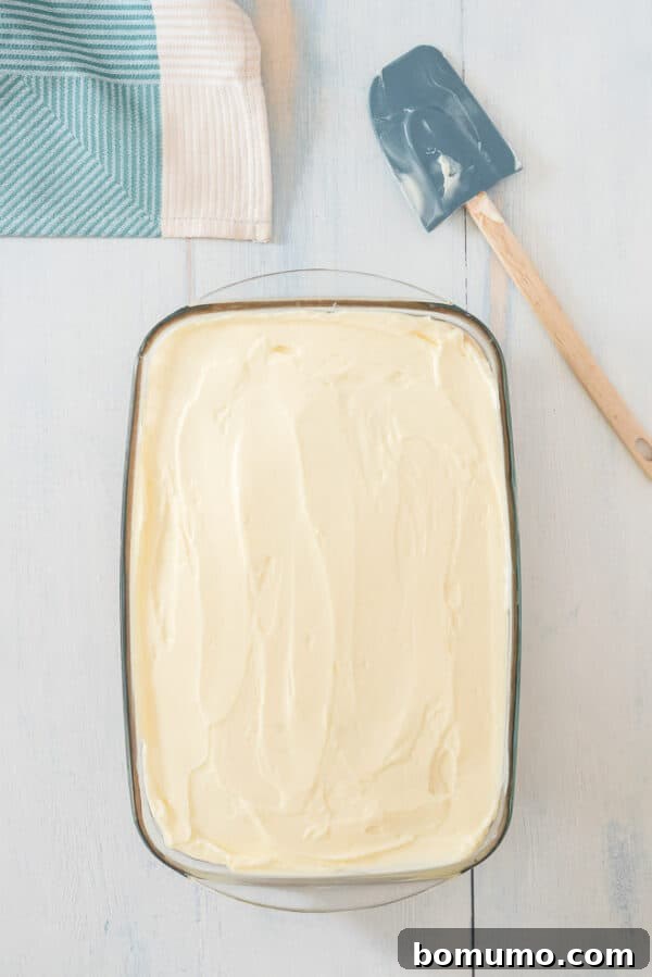 This pumpkin poke cake recipe is an easy fall dessert oozing with sweet cinnamon filling and smothered with tangy cream cheese frosting. Frosted pumpkin poke cake on a countertop.