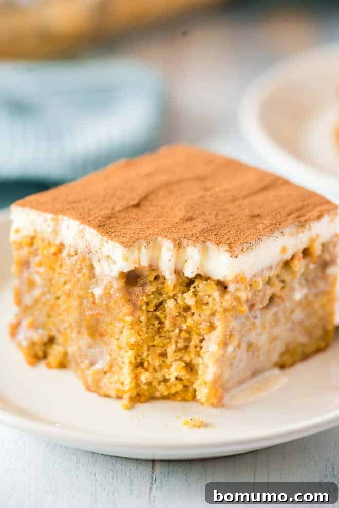 This pumpkin poke cake recipe is an easy fall dessert oozing with sweet cinnamon filling and smothered with tangy cream cheese frosting. Close up of a slice of pumpkin cake, a bite has been taken out of it with a fork.