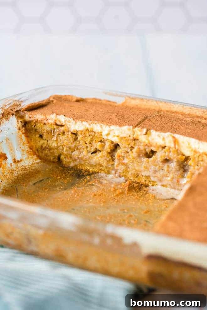 This pumpkin poke cake recipe is an easy fall dessert oozing with sweet cinnamon filling and smothered with tangy cream cheese frosting. Pumpkin poke cake in a clear baking dish, with slices missing.