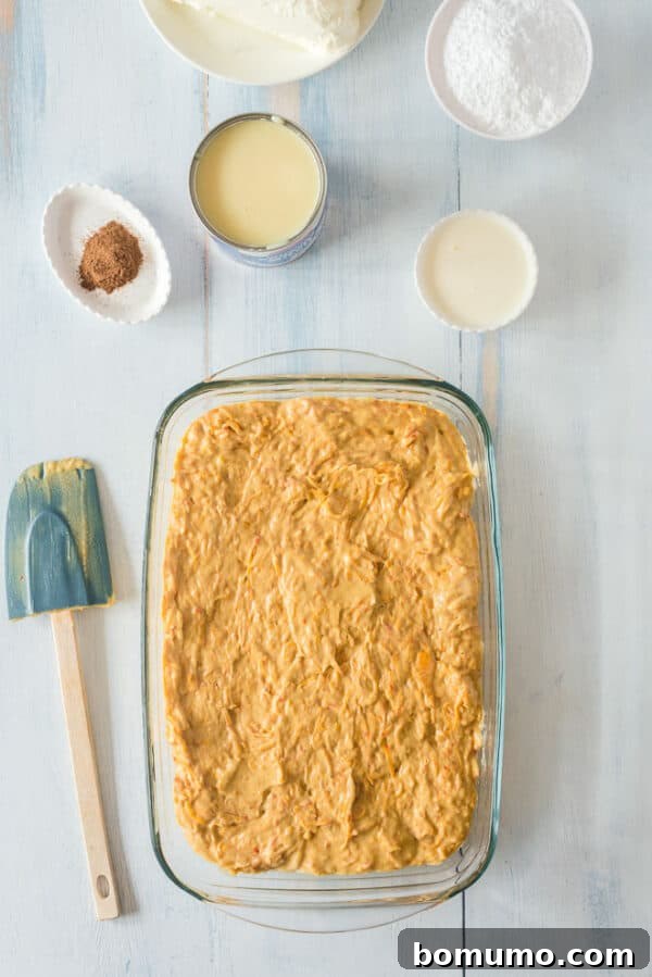 This pumpkin poke cake recipe is an easy fall dessert oozing with sweet cinnamon filling and smothered with tangy cream cheese frosting. Pumpkin poke cake batter spread into a 9x13-inch cake pan.