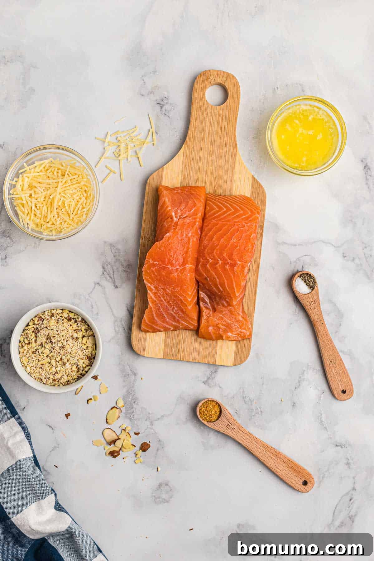An overhead shot showcasing all the fresh, high-quality ingredients laid out for making almond and Parmesan crusted salmon, including salmon fillets, almonds, Parmesan cheese, butter, and seasonings.
