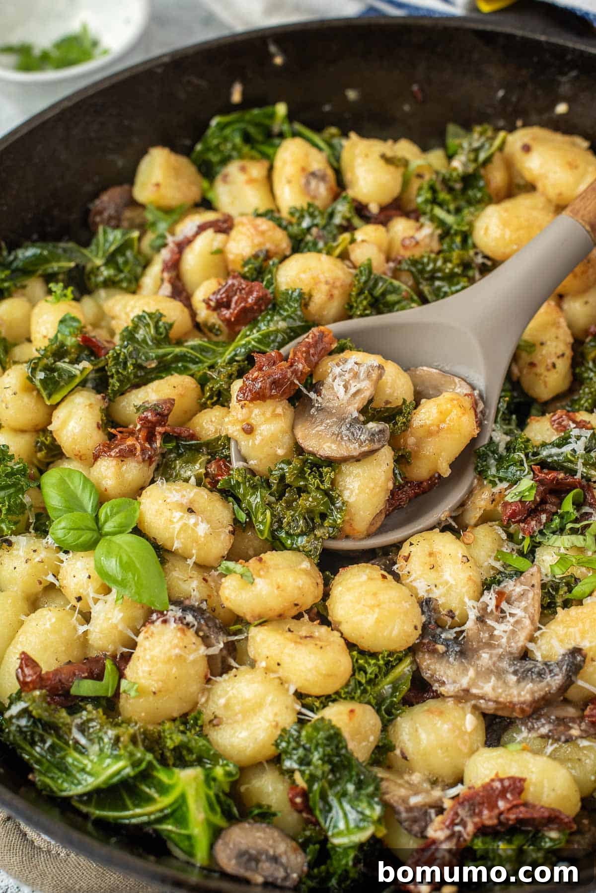Close-up view of one pan gnocchi on a serving spoon. Sun-dried tomatoes and golden gnocchi are clearly visible.