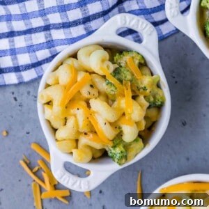 Overhead view of a small white bowl of instant pot mac and cheese with broccoli. Two other bowls are partially visible.