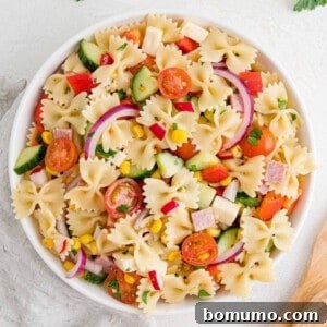 Summer pasta salad, vibrant and inviting, presented in a round white bowl.