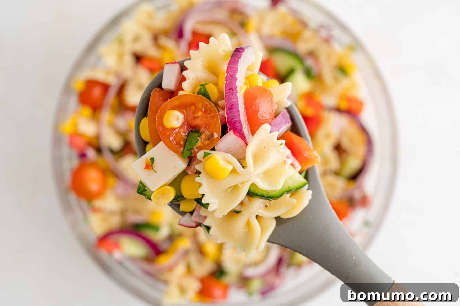 A close-up shot of a spoonful of the delightful summer pasta salad, showcasing its rich textures and colors.