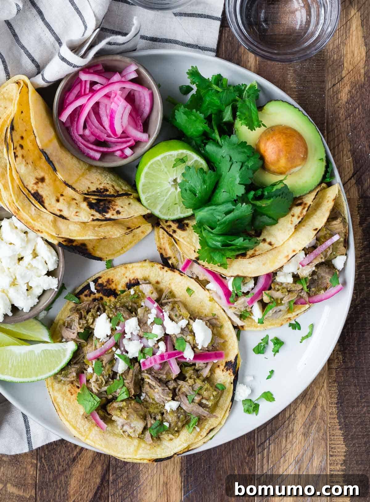 Overhead view of a platter with pork tacos and toppings.