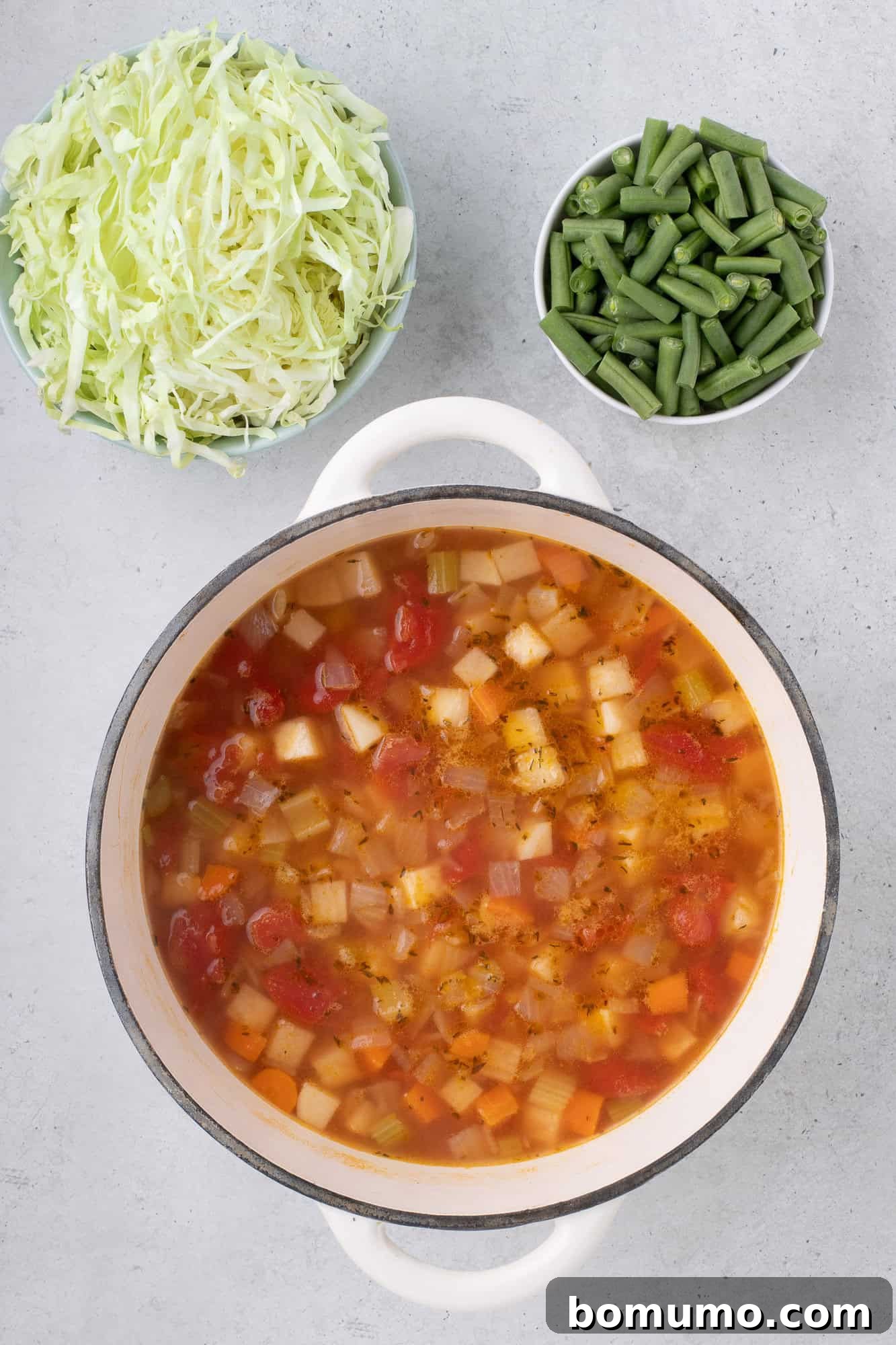 Vegetable broth, diced tomatoes, and water added to the sautéed vegetables in the pot.