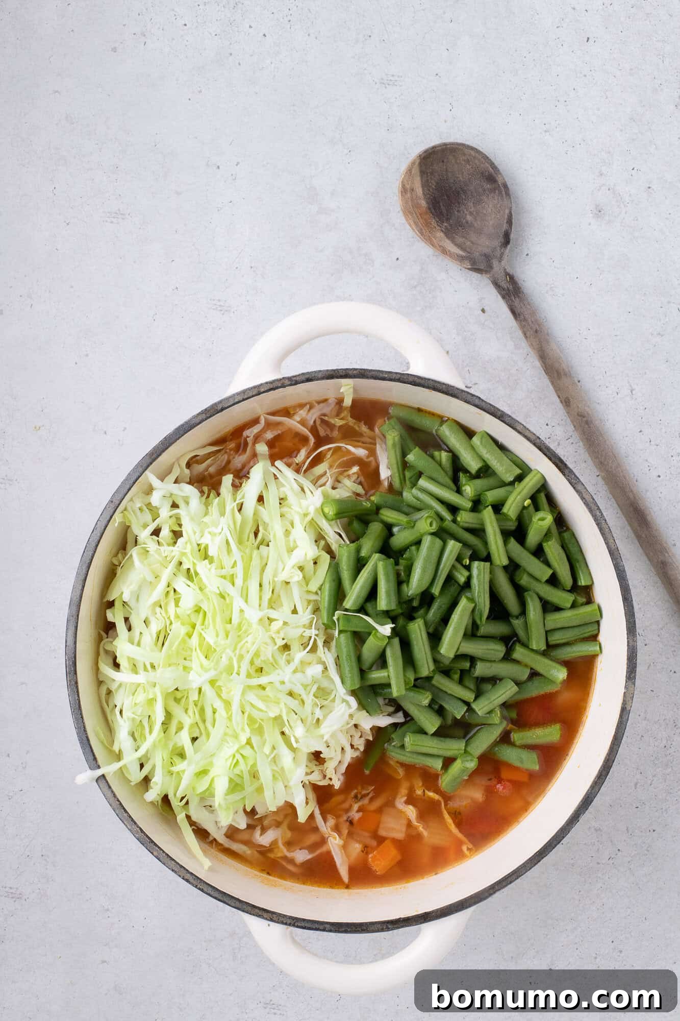 Green beans and shredded cabbage added to the simmering soup.