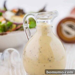 Small glass bottle of creamy maple dressing, a pepper cracker in the background.