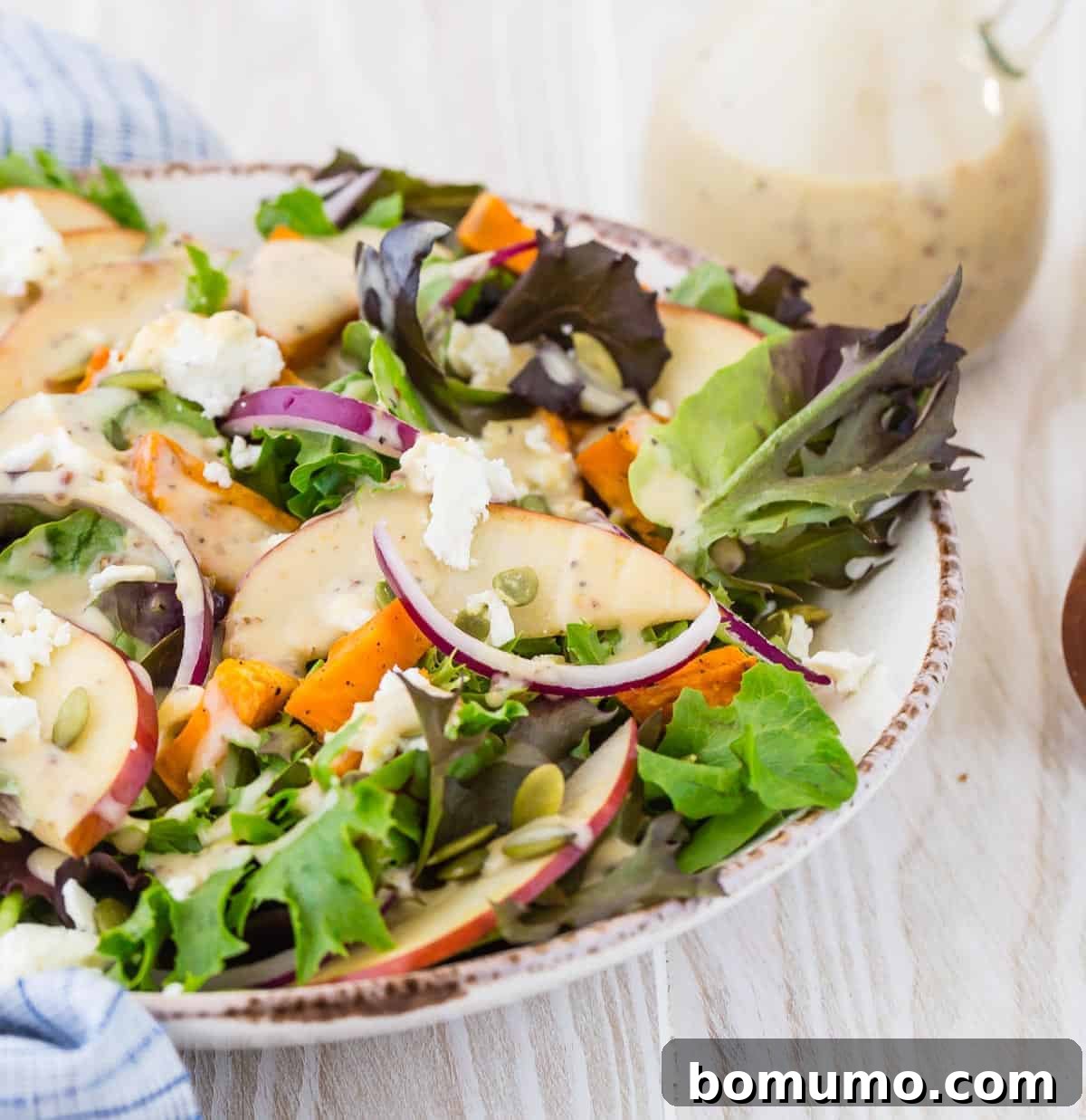 Colorful salad with creamy white dressing poured over fresh greens and toppings.