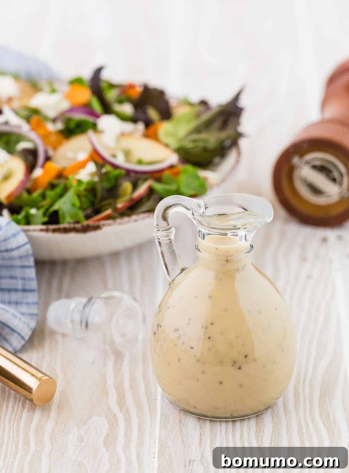 Creamy light colored dressing with black specks, in a clear glass bottle, signifying quality.