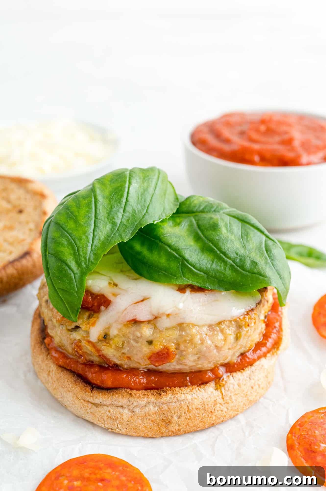 A perfectly cooked turkey burger generously topped with melted mozzarella cheese and fresh basil leaves, ready to be enjoyed.