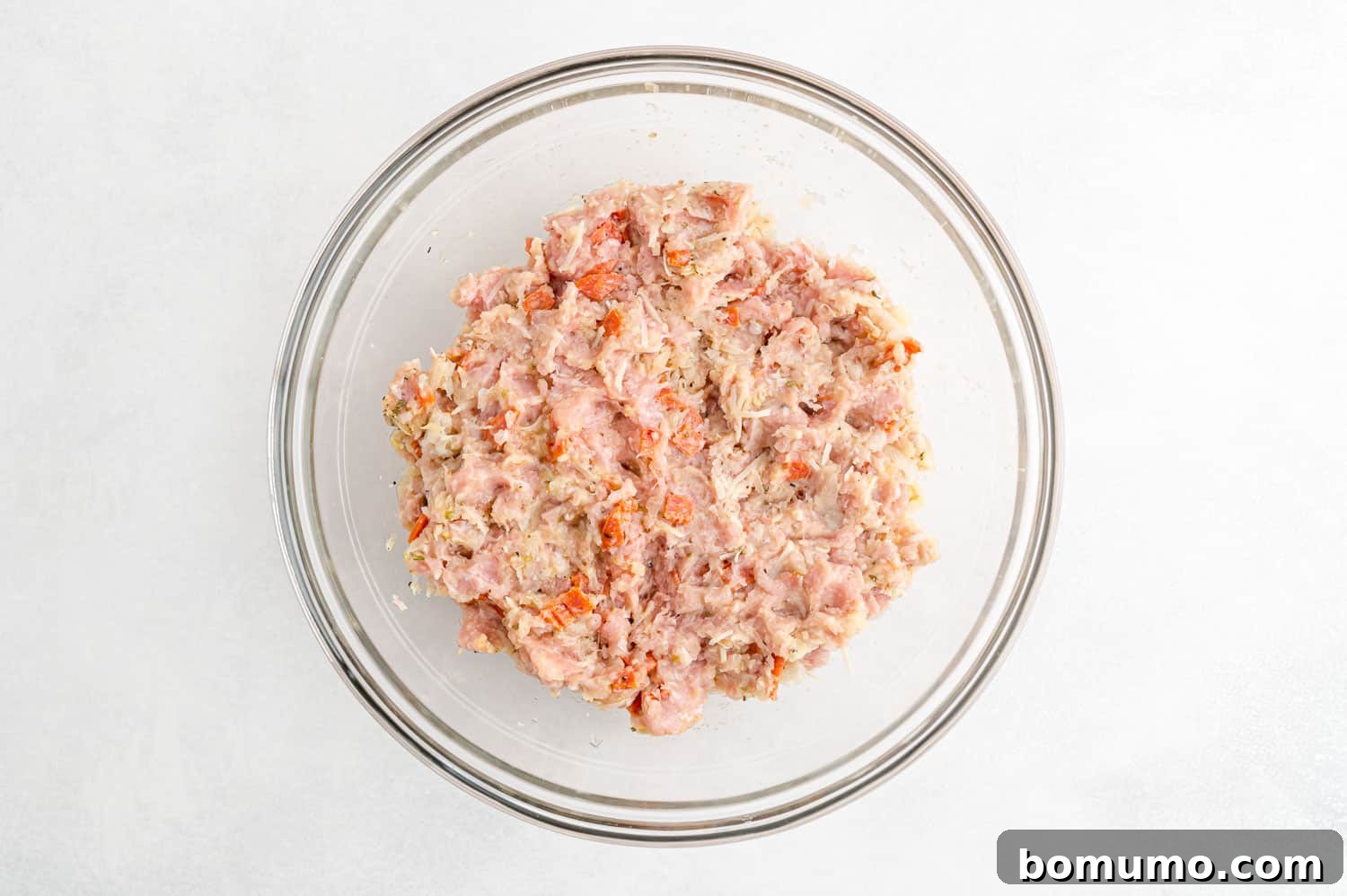 The perfectly mixed ingredients for pizza turkey burgers, ready to be formed into patties, in a clear mixing bowl.
