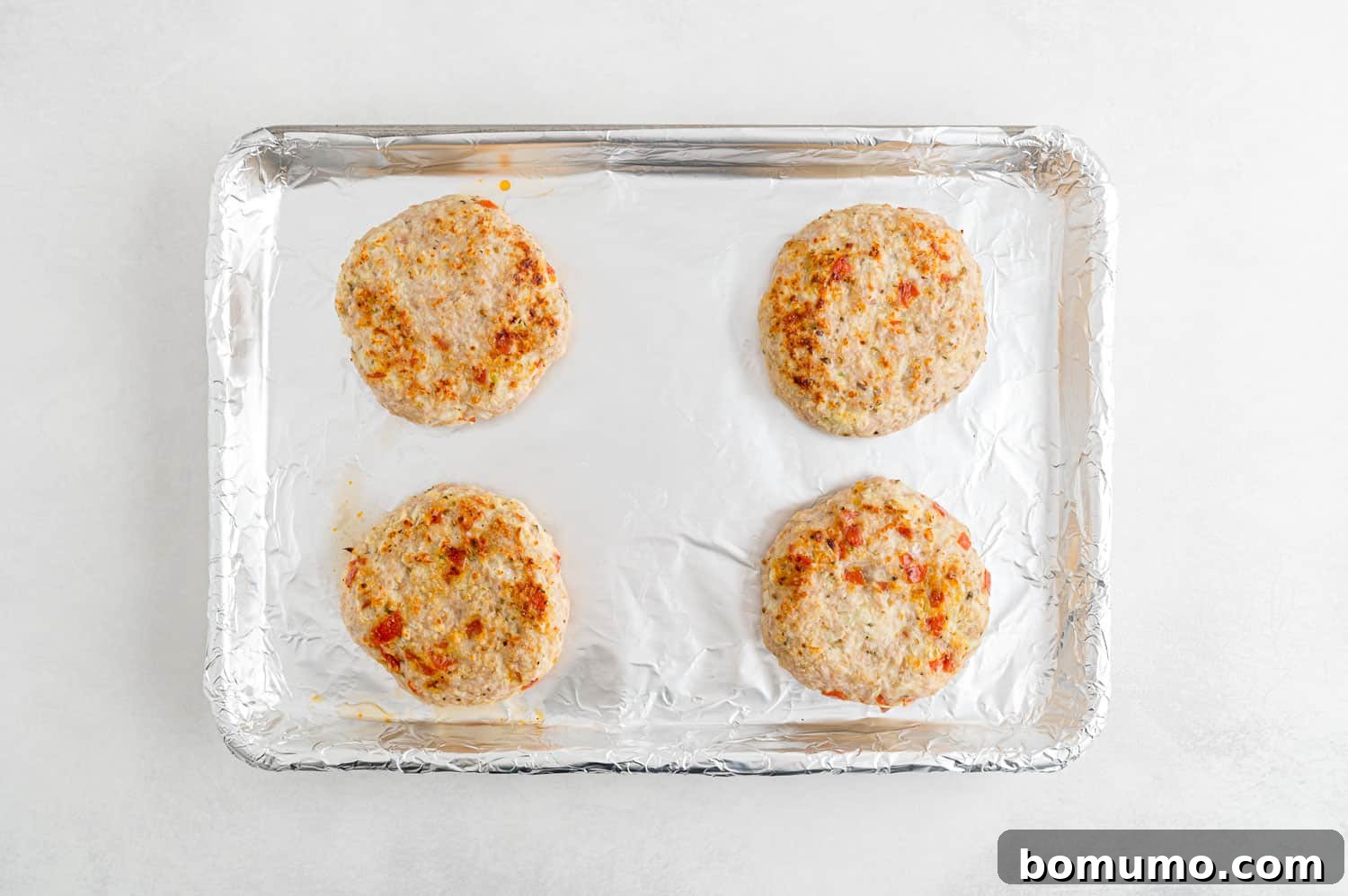 A baking sheet filled with cooked turkey burgers, browned to perfection, fresh from the oven and ready for toppings.