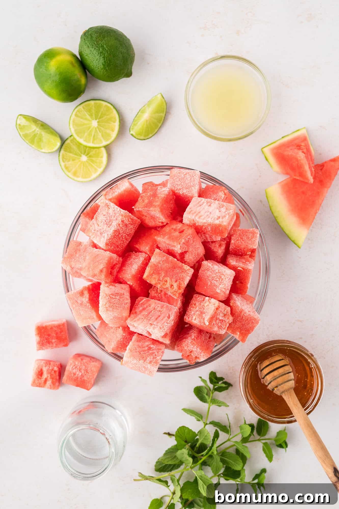 An overhead shot showcasing all the fresh and simple ingredients required to make the perfect watermelon slushie recipe, laid out on a clean surface.