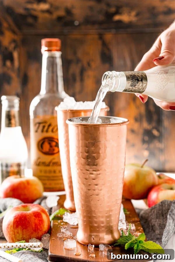 Ginger beer being poured into a copper mug, completing the base of the refreshing Apple Cider Moscow Mule.