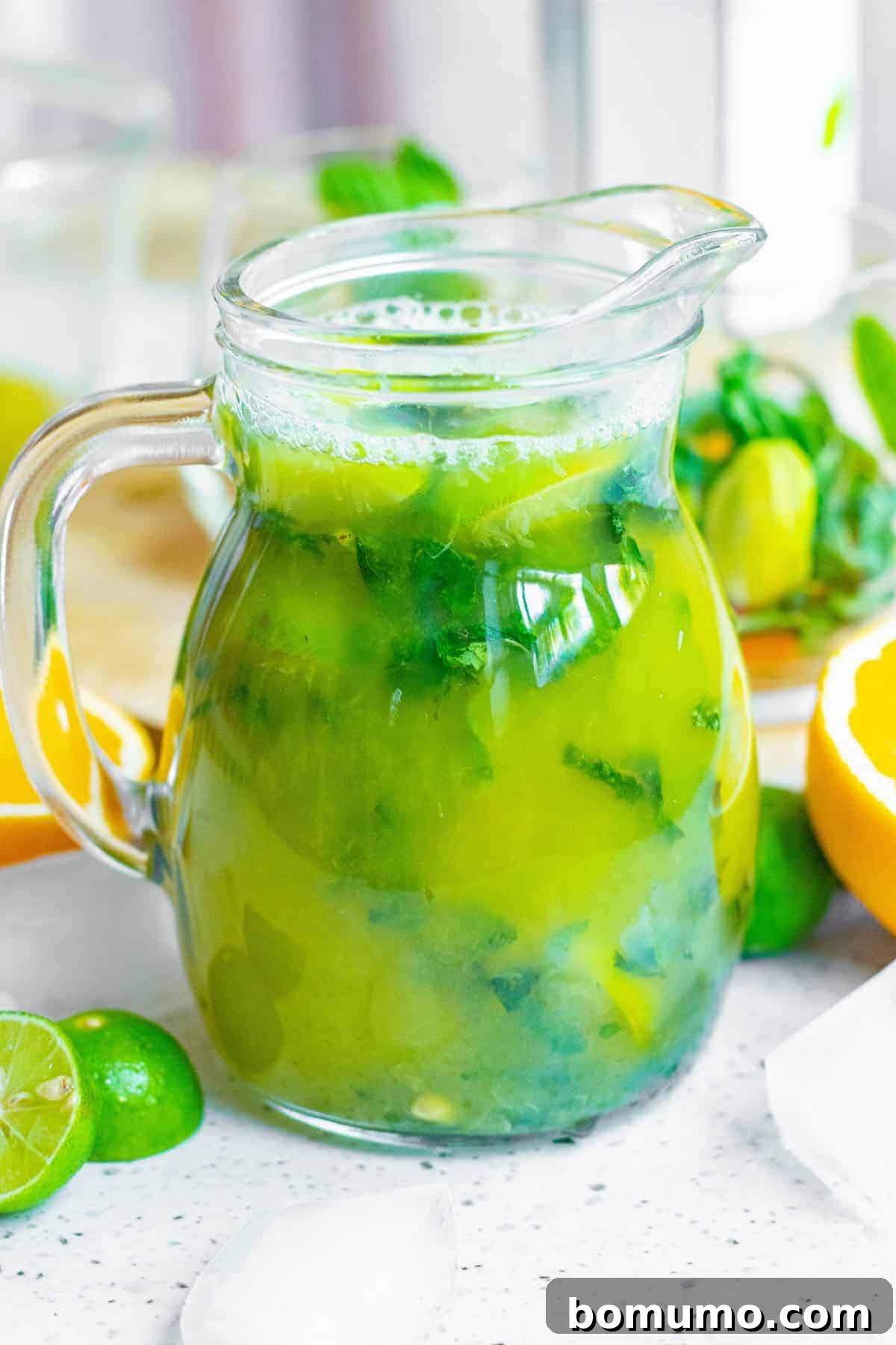 Sun-Kissed Mojito 6 A large pitcher filled with a freshly prepared orange and mint mojito mixture, sparkling with fresh ingredients and ready for individual servings.