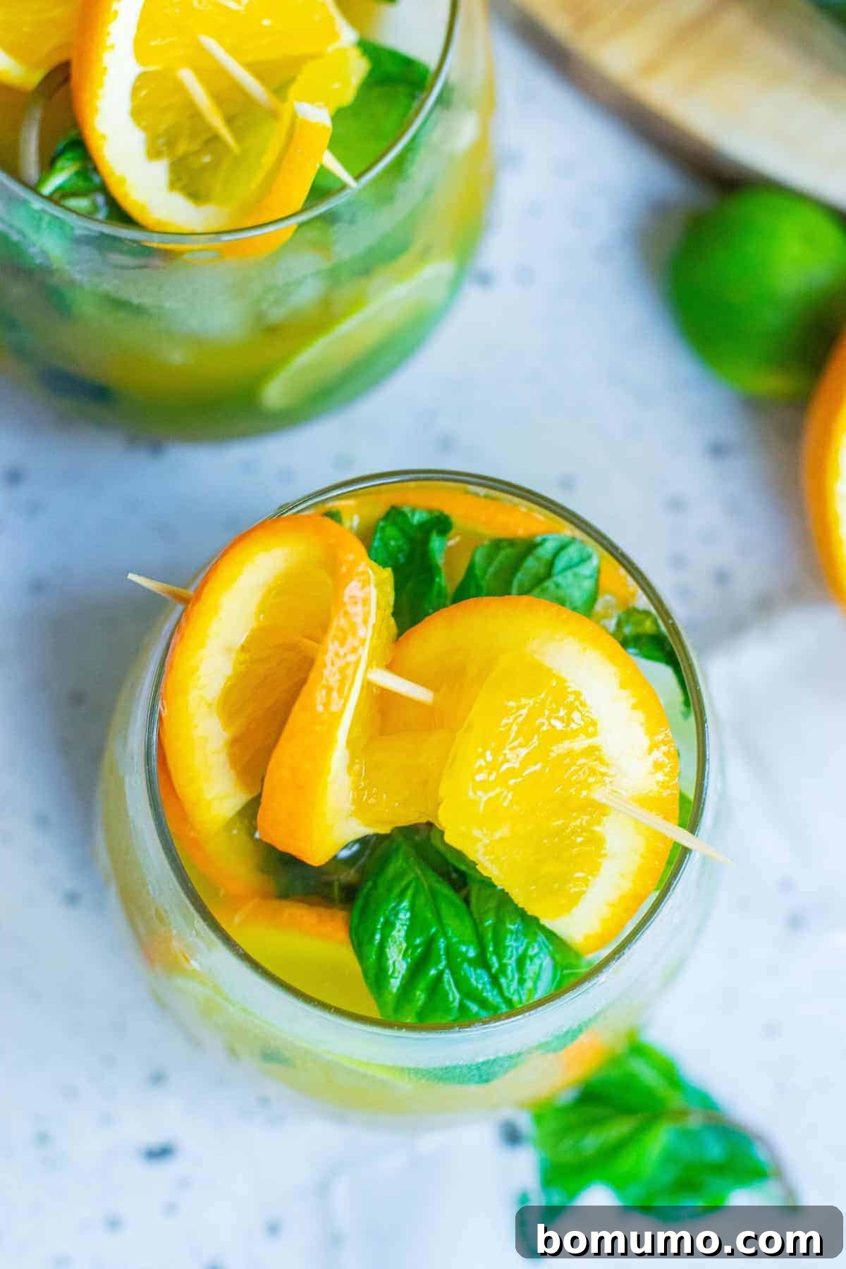 Sun-Kissed Mojito 8 An inviting overhead view of a vibrant Orange Mojito cocktail, beautifully garnished with fresh orange slices and mint sprigs in a clear glass, signifying ultimate refreshment.
