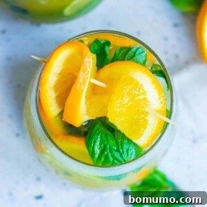 Sun-Kissed Mojito 9 Overhead view of an orange cocktail with fresh orange and mint leaves, a refreshing drink.
