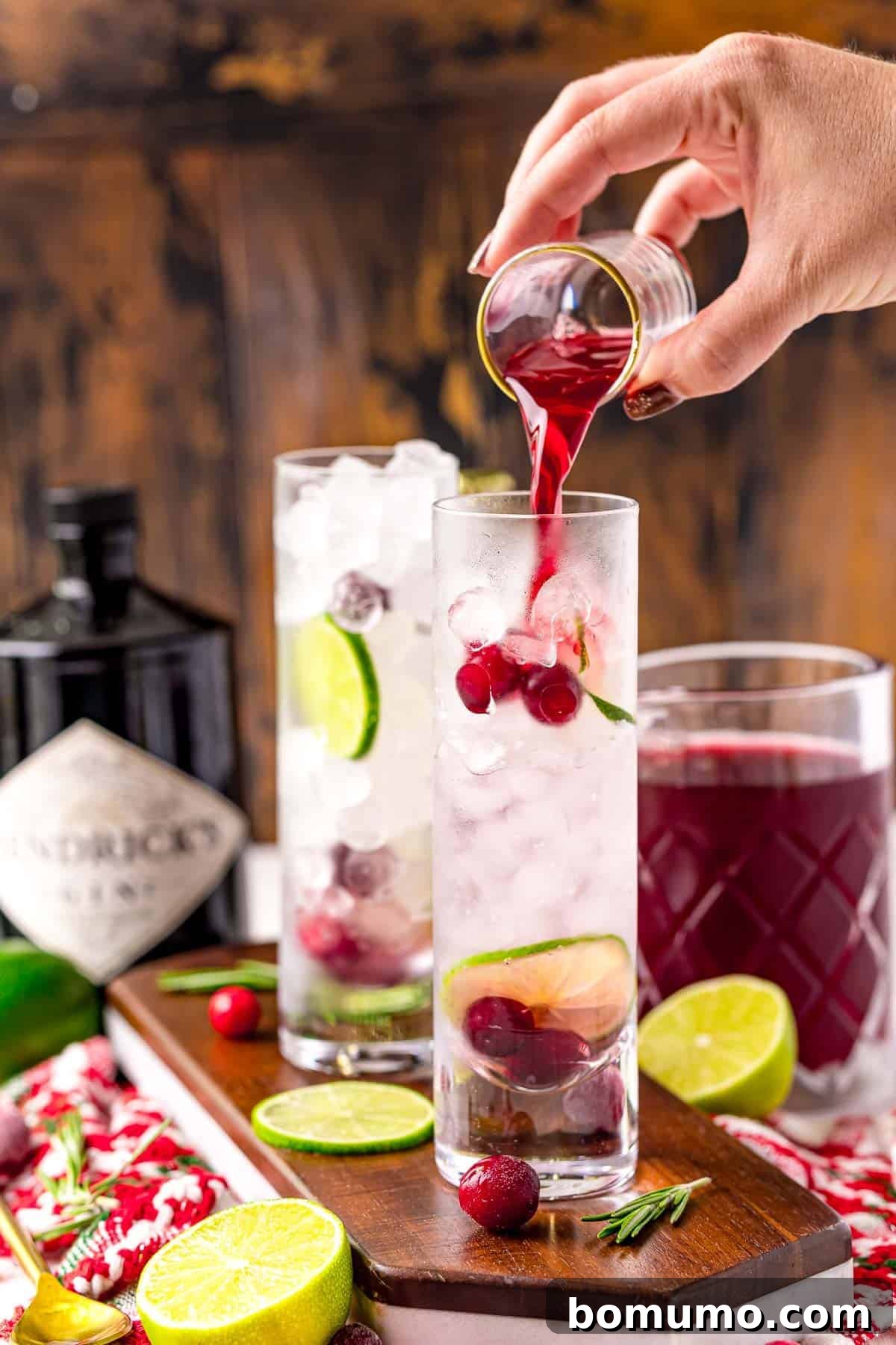 Cranberry being poured into a G&T cocktail.
