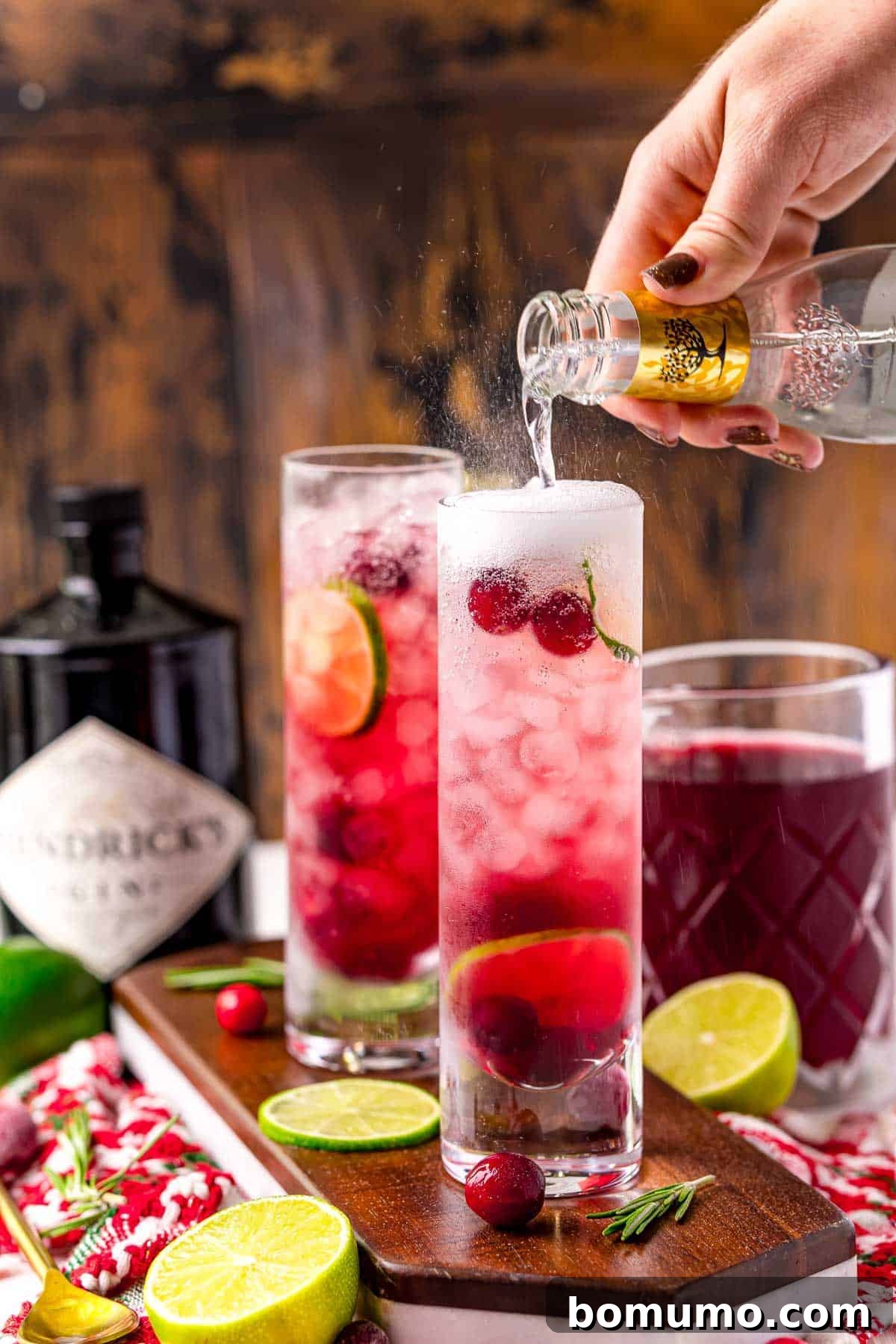 Tonic water being added to a red cocktail.